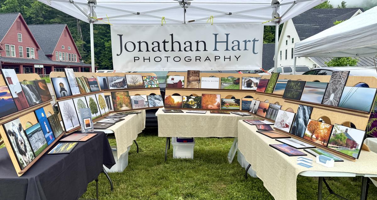 Jonathan Hart Photography booth — display walls of laminated photography prints under a market tent