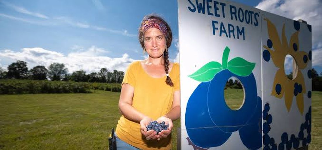 Sweet Roots Farm — Jane MacLean with the day's blueberries at the farm sign
