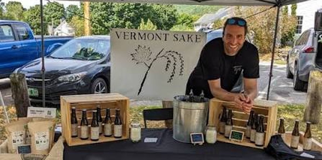 Vermont Sake at the market — Andrew Baker behind the booth with the Vermont Sake banner